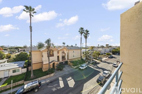 A residential area with a house, palm trees, and parked cars.