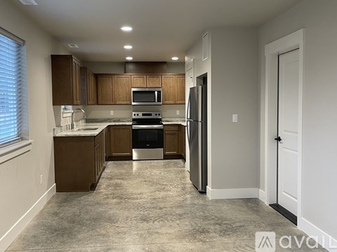 A kitchen with brown cabinets and a black refrigerator.
