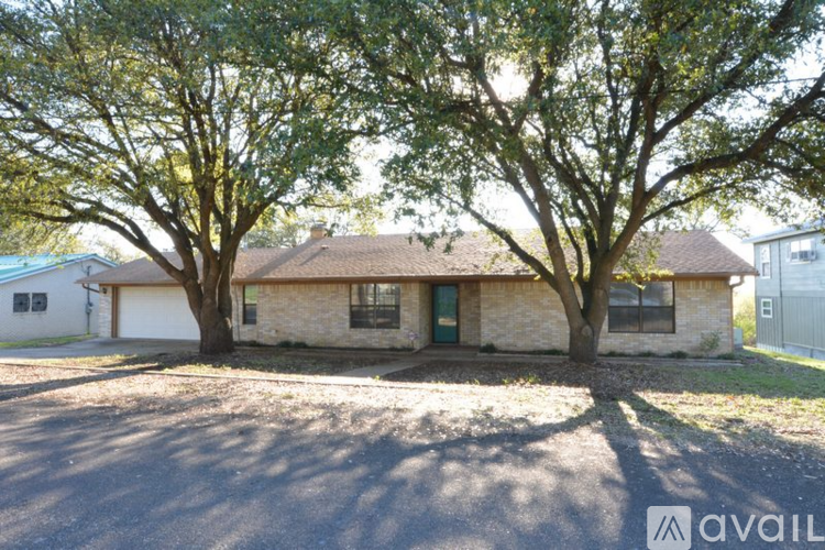 A house with a driveway and two trees in front.