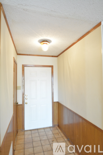 A hallway with a white door and tiled floor.