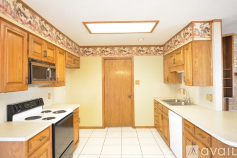 A kitchen with wooden cabinets and a tiled floor.