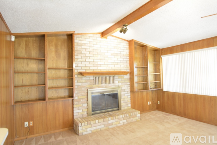 A living room with a fireplace and wooden shelves.