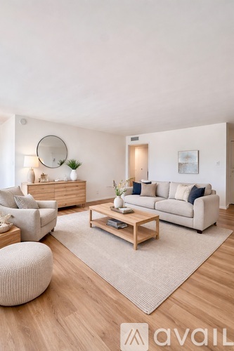A living room with a white couch, a wooden coffee table, and a round mirror on the wall.