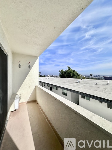 A balcony with a view of the rooftops and trees.