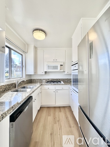 A kitchen with white cabinets and a granite countertop.