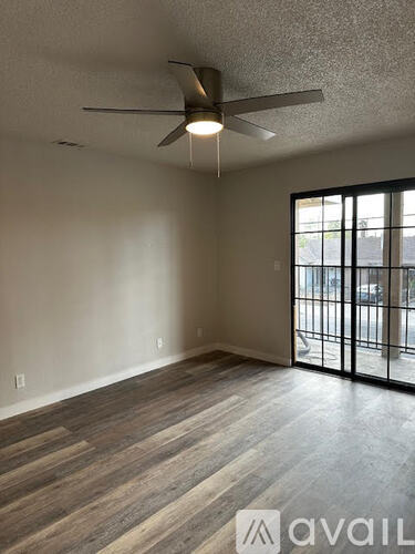A room with a ceiling fan and a sliding glass door leading to a balcony.