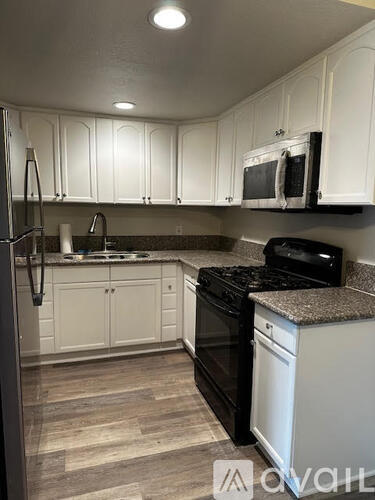 A kitchen with white cabinets and black appliances.