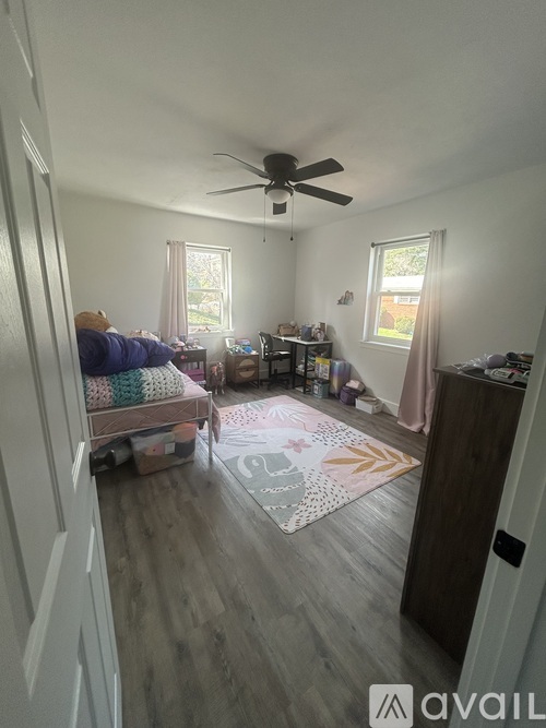 A living room with a couch, a rug, and a ceiling fan.