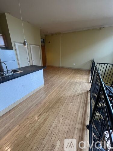 A kitchen with wooden floors and a black railing.