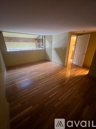 A room with wooden flooring and a window with a view of a brick wall outside.