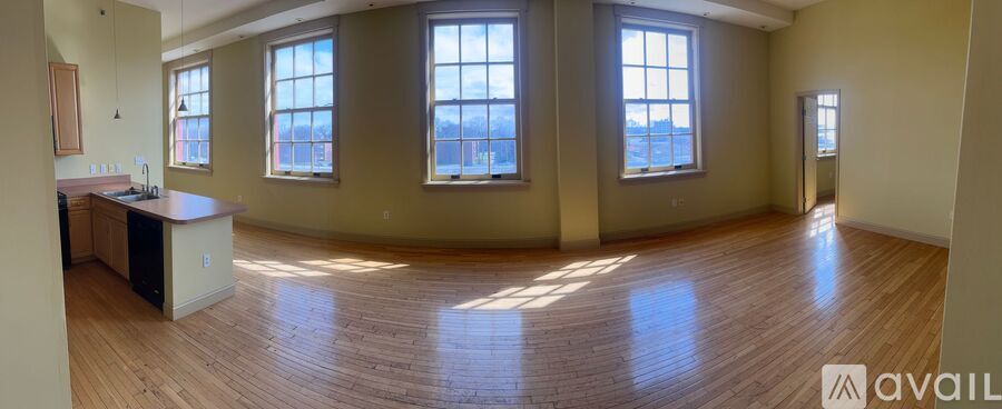 A large empty room with wooden floors and three windows.