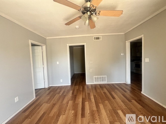A room with a ceiling fan and wooden floors.