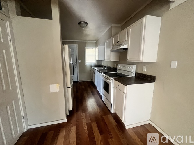 A kitchen with white cabinets and a wooden floor.