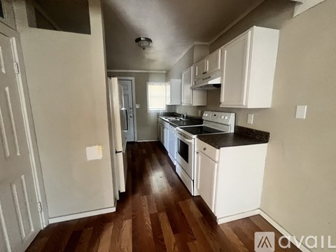 A kitchen with white cabinets and a wooden floor.