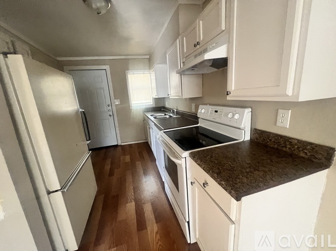 A kitchen with white appliances and wooden floors.