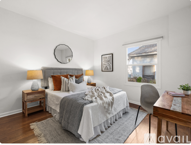 A bedroom with a bed, a chair, a table, and a window.
