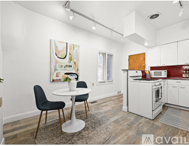 A kitchen with a white table and chairs and a painting on the wall.