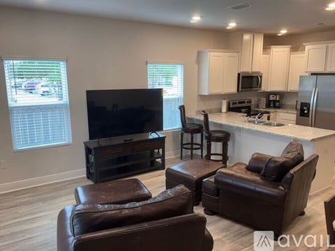 A living room with brown leather furniture and a flat screen TV.