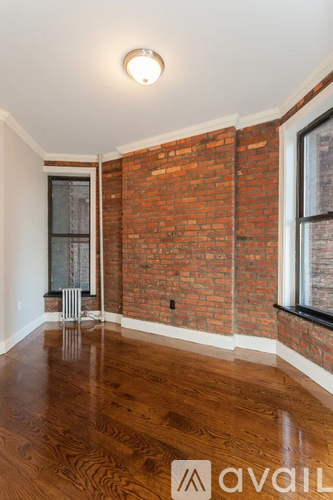 A room with a wooden floor and a brick wall.