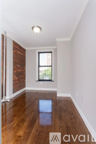 A room with wooden floors and a window with a brick wall on the side.