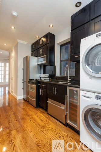 A modern kitchen with dark wood cabinets and stainless steel appliances.