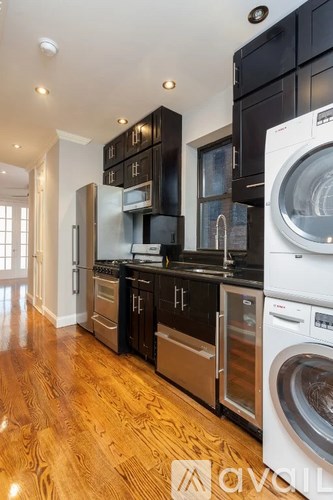 A modern kitchen with dark wood cabinets and stainless steel appliances.