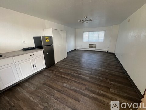A kitchen with white cabinets and a black fridge.