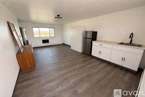 A kitchen with white cabinets and a wooden floor.
