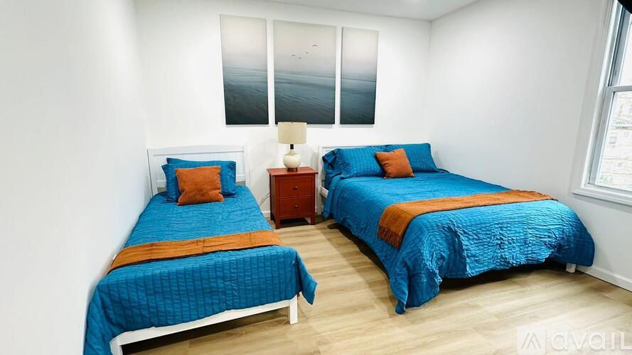 Two twin beds with blue bedspreads and orange accents in a room.