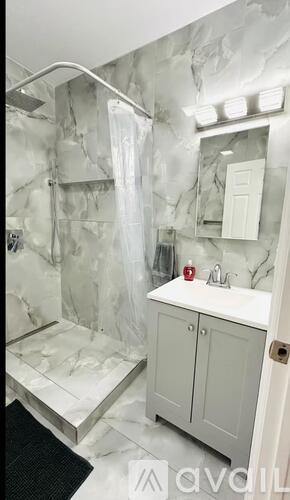 A bathroom with marble walls and a walk-in shower.