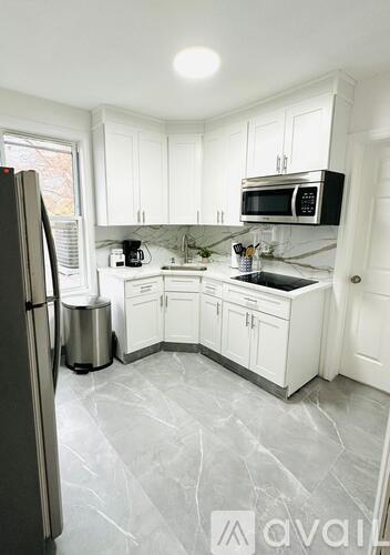 A kitchen with white cabinets and a marble floor.