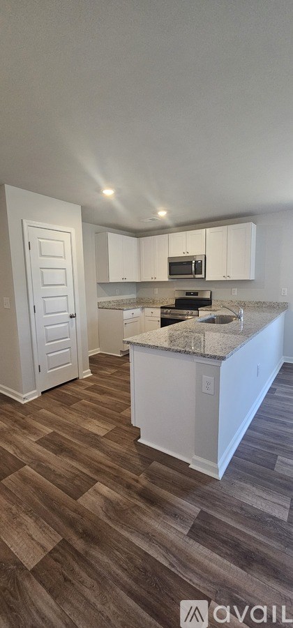 A kitchen with white cabinets and a wooden floor.