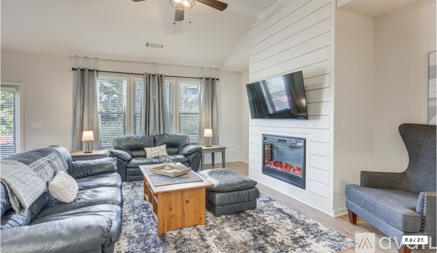 A living room with a grey couch, a coffee table, and a flat screen TV mounted on the wall.