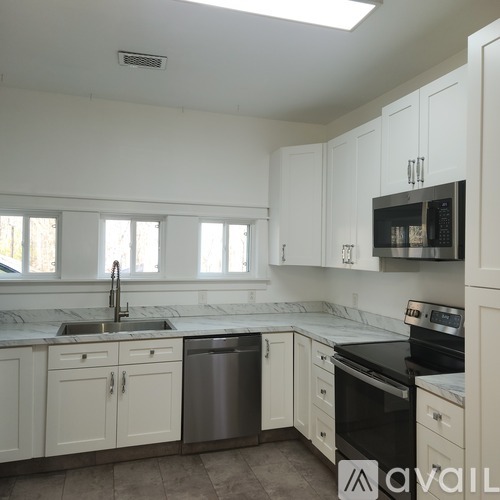 A kitchen with white cabinets and black appliances.