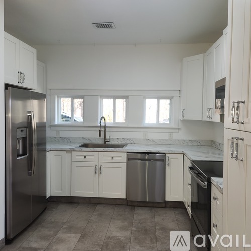 A kitchen with white cabinets and a stainless steel refrigerator.
