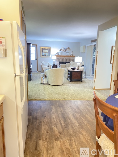 A white refrigerator is in the kitchen of a well-lit, spacious apartment.