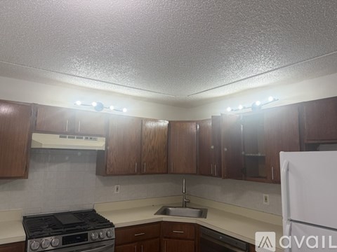 A kitchen with wooden cabinets and a white stove top oven.