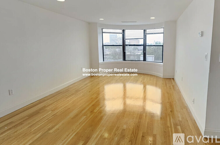 A spacious room with wooden flooring and large windows.