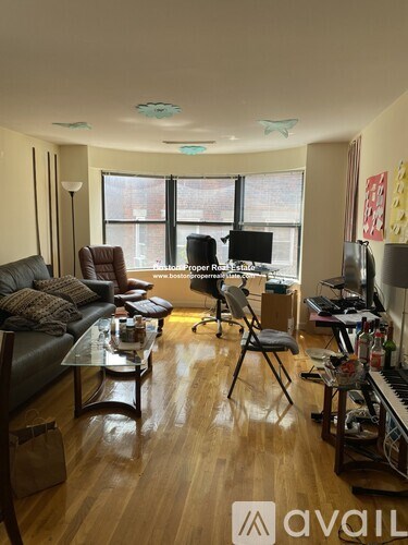 A living room with a brown leather couch and a wooden floor.