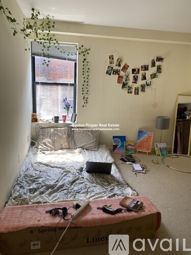 A messy bedroom with a bed covered in a blanket and a wall decorated with pictures.