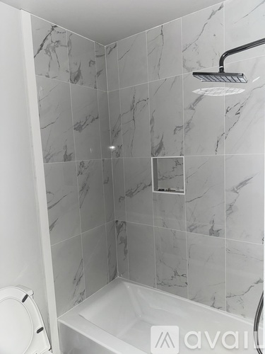 A white toilet is next to a marble tiled shower.