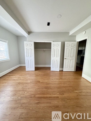 A room with wooden flooring and white walls, with a large open doorway.