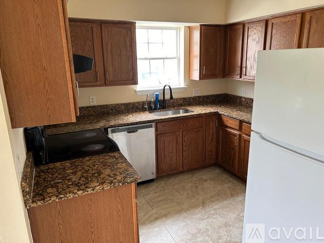A kitchen with brown cabinets and a granite countertop.