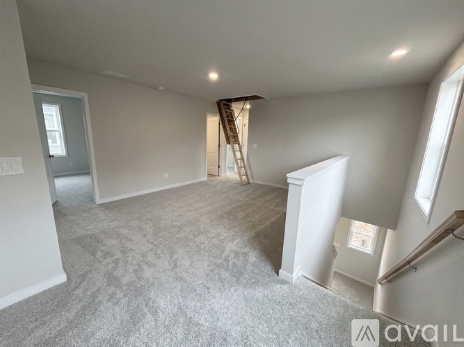 A spacious room with a carpeted floor and a staircase leading to another level.