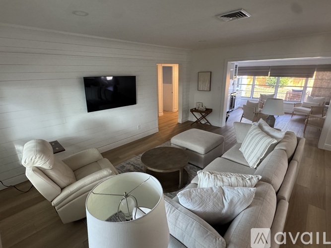 A living room with a white sofa, a white armchair, and a white ottoman.