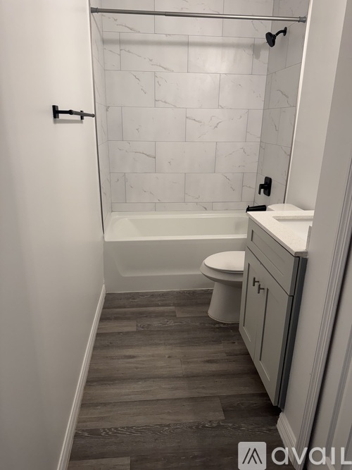 A bathroom with a marble tile shower and a wooden floor.