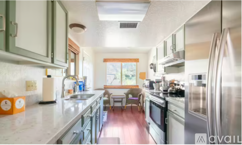 A kitchen with a refrigerator, sink, and stove.