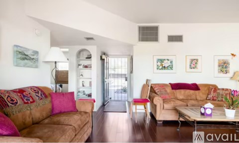 A living room with a brown couch and a red pillow.