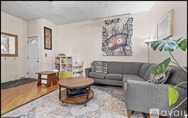 A living room with a grey couch, a coffee table, and a painting on the wall.