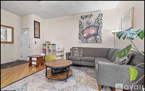 A living room with a grey couch, a coffee table, and a painting on the wall.